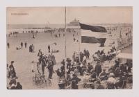 Crowded beach scene with people on the sand with water in the background