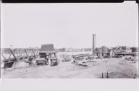 Workers and trucks with river and bridge in back